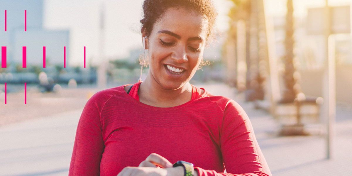 Mulher, sorrindo, fazendo exercício físico e olhando para seu relógio