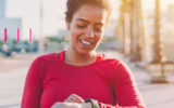 Mulher, sorrindo, fazendo exercício físico e olhando para seu relógio