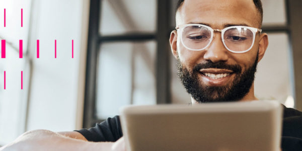 Homem de óculos, sorrindo, e mexendo em tablet