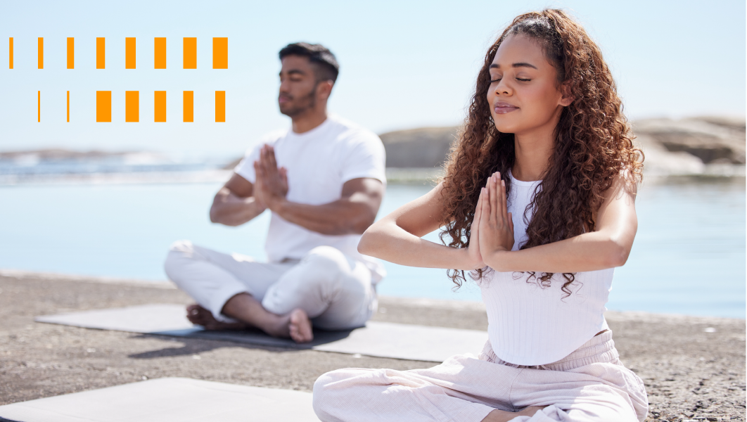 Um casal a beira mar sentados meditando