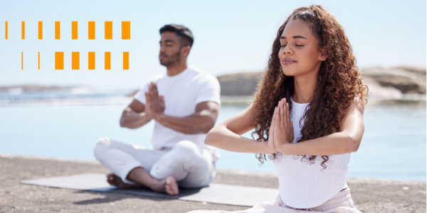 Um casal a beira mar sentados meditando