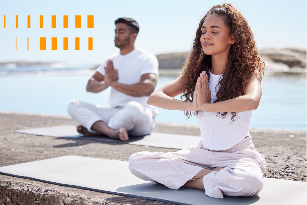 Um casal a beira mar sentados meditando